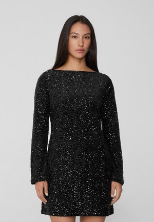 Schwarzes Langarmkleid mit strukturierten Pailletten, quadratischem Ausschnitt und figurbetontem Schnitt, der den Gesamtschimmer und die Tiefe verstärkt.