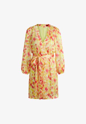 Vaatteet, jotka valuvat kauniisti ja joissa on pitkät puffhihat, valmistettu keltaisesta kankaasta, joka on koristeltu pinkeillä ja oransseilla sävyillä kukkakuviolla, sekä solmittavalla vyöllä.