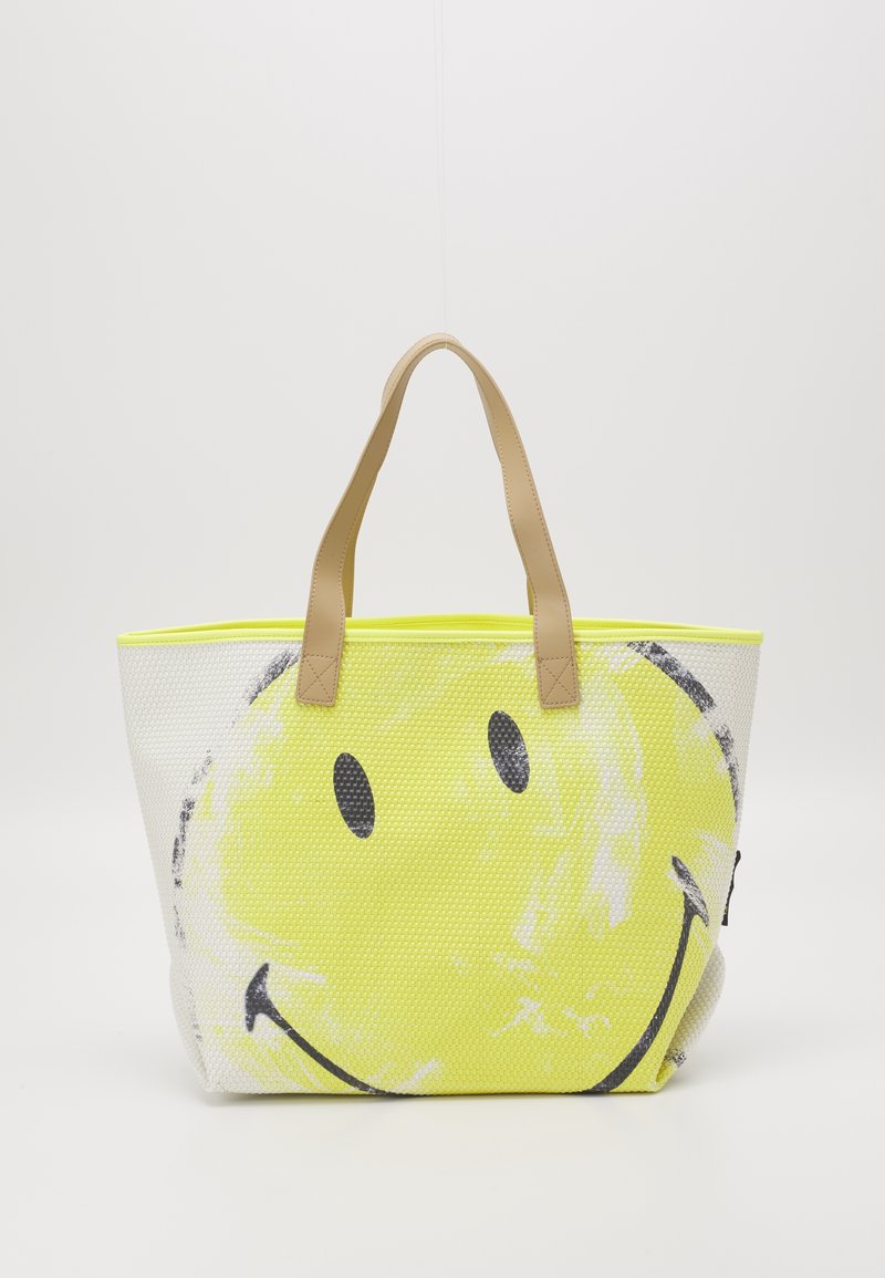 Grand sac fourre-tout en maille texturée, avec un imprimé visage souriant jaune. Poignées en cuir synthétique marron et bordure néon.