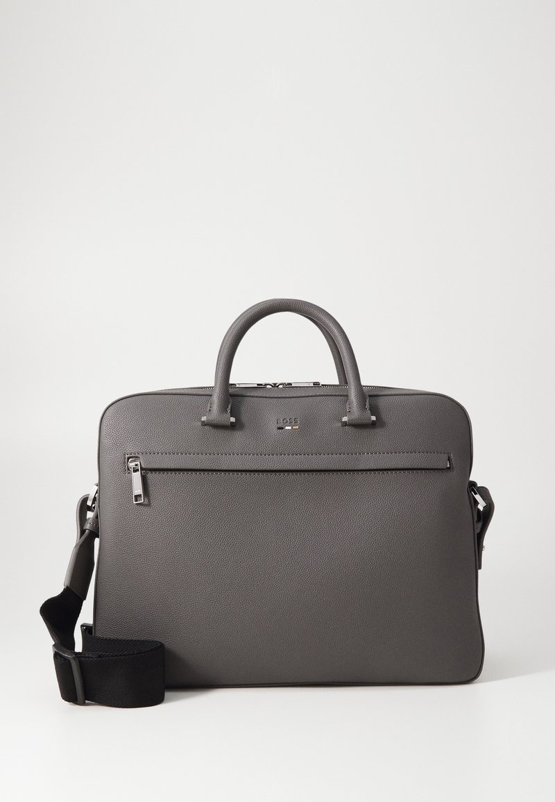 Graue Lederhandtasche mit strukturiertem Design, doppelten Griffen, abnehmbarem Schultergurt und einer vorderen Reißverschlusstasche. Texturierte Oberfläche und silberne Hardware.
