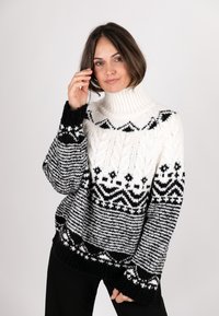 Knitted sweater featuring a high collar in black and white, with fair isle patterns, thick texture, and long sleeves with ribbed cuffs.