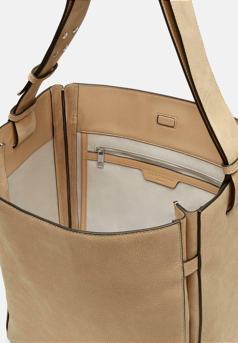 Beige Leder-Tote mit einer glatten Textur. Verfügt über eine mit einem Reißverschluss verschlossene Innentasche und ein kontrastierendes, helleres Innenfutter. Verstellbarer Schultergurt inklusive.