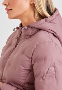 Light pink puffer jacket with a zippered front, adjustable hood, and logo on the left shoulder. Smooth, quilted texture.