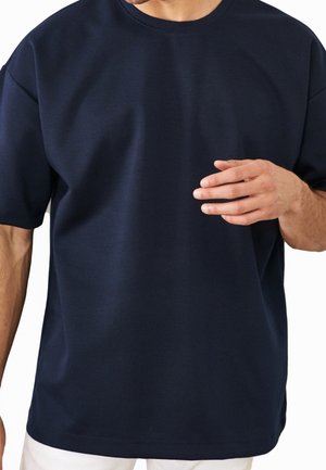 Camiseta de manga corta azul marino, hecha de tela suave, con un cuello redondo y un corte holgado. Diseño simple sin patrones visibles.