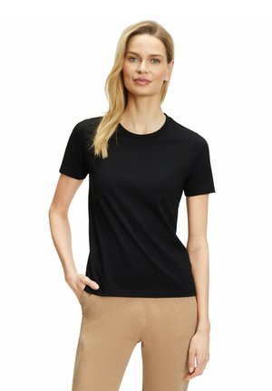 Zwart T-shirt met korte mouwen, gemaakt van gladde stof, met een ronde halslijn en een getailleerde pasvorm. Gekoppeld aan lichtbruine broek.