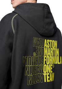 Czarna bluza z kapturem z dużym żółtym napisem "ASTON MARTIN FORMULA ONE TEAM" oraz kontrastowymi przeszyciami wzdłuż kaptura.