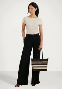 Beige στενό τοπ, μαύρο ψηλόμεσο παντελόνι με φαρδιά πόδια και μια ριγέ τσάντα tote σε μαύρο και κρέμ, συνδυασμένα με ανοιχτόπατα τακούνια.