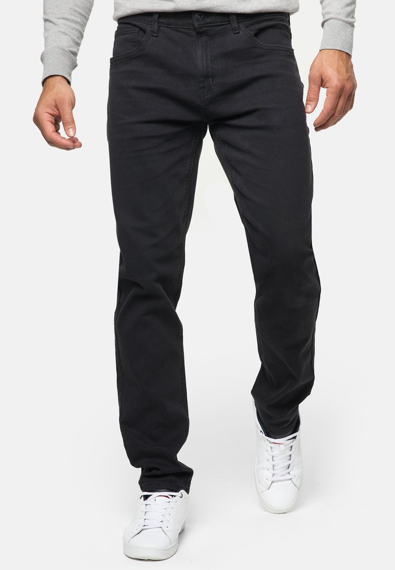 Vaqueros de mezclilla de algodón negros con un diseño de pierna recta, estilo de cinco bolsillos y detalles de costura sutiles. Combinados con zapatillas blancas.