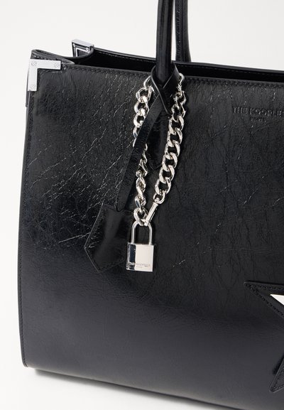 Sac fourre-tout en cuir noir avec une finition texturée, quincaillerie en argent, détail en chaîne et un petit cadenas. Présente un accent en forme d'étoile.