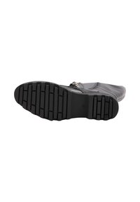 Boot din piele neagră prezentat din talpă, având un model adânc de profil și detalii cu cataramă pe lateral, pe un fundal alb.