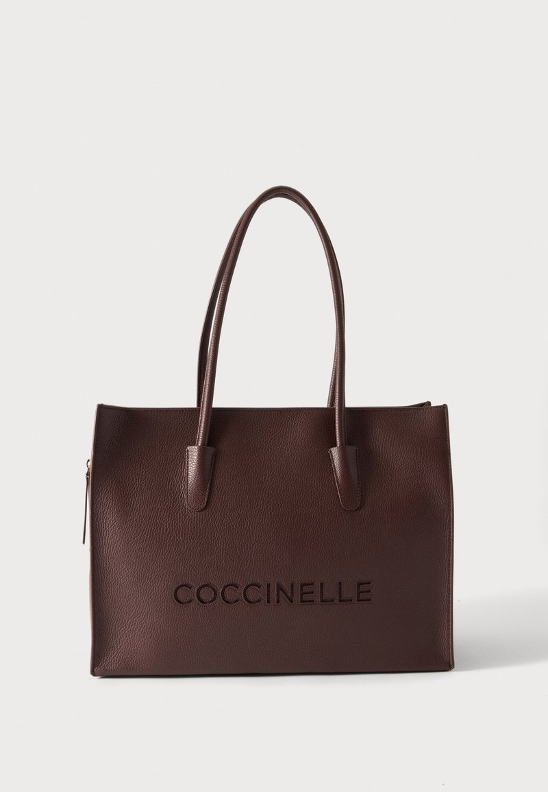 Sac cabas en cuir texturé marron foncé avec deux poignées et « COCCINELLE » embossé à l'avant sur un fond uni.