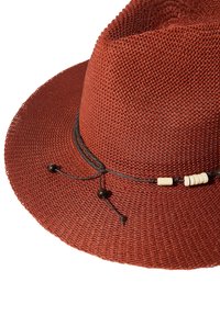 Terrakotowy pleciony kapelusz słomkowy z czarną wstążką z beżowymi i ciemnymi koralikami, szerokim rondem i fakturowym wykończeniem.