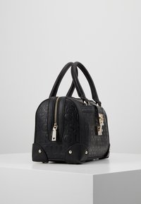 Zwarte neplederen handtas met reliëflogo, gouden hardware, ritssluiting, ronde vorm en metalen voetaccenten. Afmetingen: klein.