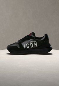 Baskets noires Dsquared2 avec semelle épaisse, lacets et texte blanc "ICON" et "DSQUARED2" sur le côté, exposées sur une surface claire.