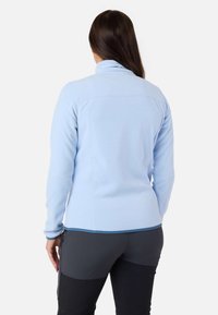 Jasnoniebieska polarowa kurtka z wysokim kołnierzem, charakteryzująca się gładką fakturą i dopasowanym krojem. Widok z tyłu ukazuje czystą sylwetkę oraz szwy.