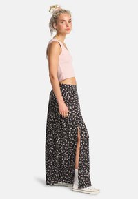 Sort blomstrede maxiskirt med slidser, letvægts stof, parret med en lyserød cropped tanktop. Hvite high-top sneakers fuldender looket.