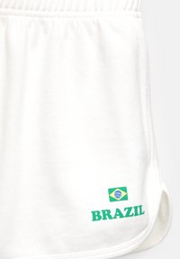 Weiße Sportshorts mit elastischem Bund. "BRAZIL" in grüner Schrift gedruckt, mit einer kleinen brasilianischen Flagge auf der linken Seite. Weiche Textur.
