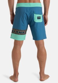 Pantalones de baño en azul y verde menta con ribete estampado y un bolsillo trasero que muestra una etiqueta de logo. Fabricados en un tejido ligero y de secado rápido.