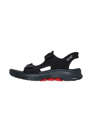 Sandalias negras con un diseño transpirable, correas de velcro y detalles recortados. Cuentan con una suela acolchada flexible con acentos rojos.