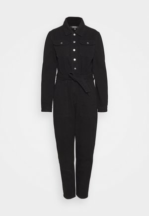 Combinaison noire à manches longues avec boutons argentés sur le devant, poches poitrine, col à revers, ceinture à nouer à la taille et pantalon à jambes droites.