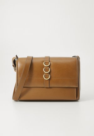 Brown leather crossbody bag with a front flap, dual circular gold hardware, and adjustable strap. Smooth texture, minimalist design.