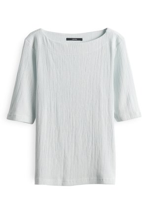 Haut bleu clair texturé avec un large col et des manches courtes. Le tissu présente un motif subtil et irrégulier dans l'ensemble.