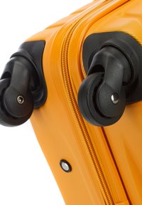 Valise rigide jaune avec une surface texturée, fermeture éclair latérale et deux roues pivotantes noires pour une maniabilité aisée.