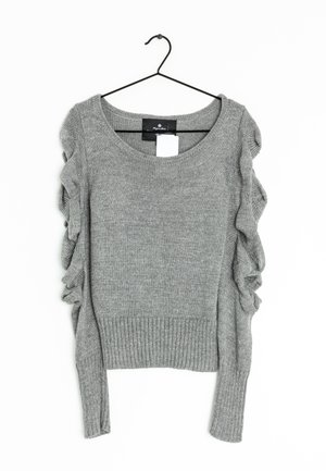 Pull en tricot gris avec ourlet côtelé et manches longues, comportant des accents froncés le long des épaules. Accroché sur un crochet noir.