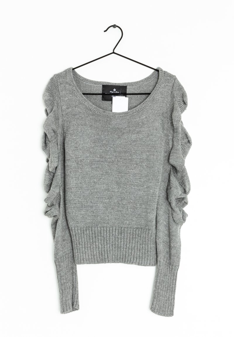 Grå strikket sweater med ribbestrikket kant og lange ærmer, der har bølgede detaljer langs skuldrene. Hænger på en sort krog.