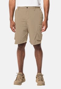 Beige cargoshorts med avslappnad passform, med fickor på sidorna, tillverkade av lätt material, i kombination med beige vandringsskor.
