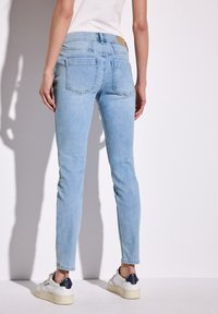 Jeans skinny azzurro chiaro con una texture liscia, design a cinque tasche e una patch in pelle con il marchio nella parte posteriore della vita.