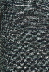 Tessuto testurizzato con una miscela di fili blu scuro, verde e argento, caratterizzato da un motivo tessuto e una leggera lucentezza sulla superficie.