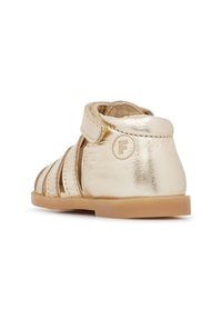 Złota skórzana sandał ze odsłoniętymi bokami i amortyzowaną piętą, wyposażony w pasek na rzep oraz gumową podeszwę z okrągłym logo.