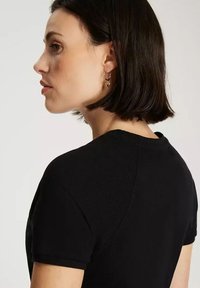 Czarna koszulka z krótkim rękawem o teksturowanej tkaninie. Posiada klasyczny okrągły dekolt i delikatne detale na ramionach. Prosty design.