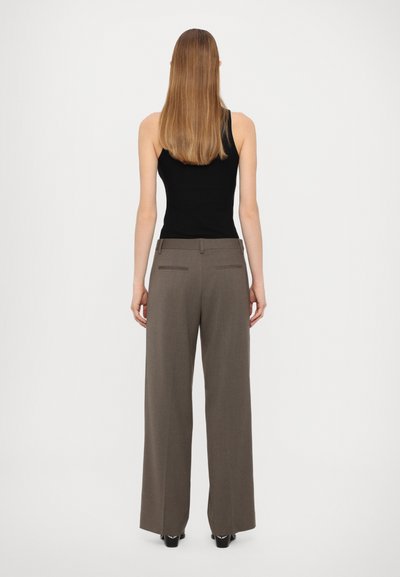 Pantalons à jambes larges en tissu gris, avec une texture lisse, présentant des détails de poches arrière et une coupe décontractée. Associés à un débardeur noir.
