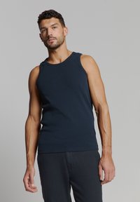 Marineblauwe mouwloze tanktop van katoen, met een ronde hals en een getailleerde pasvorm. Gladde textuur met strakke lijnen.