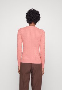 Pull rose en maille torsadée avec manches longues et ourlet côtelé. Présente un motif texturé sur toute la surface et un col rond.