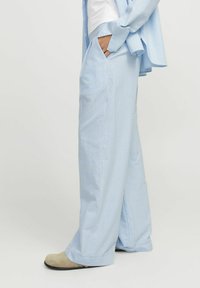 Gaiši zili svītraini plataji svārki ar sānu kabatām un mīkstu tekstūru. Pielecoša jostasvieta, brīva forma un nedaudz izplestās malas.