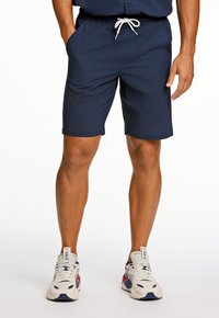 Marineblauwe shorts met een elastische tailleband en trekkoord, gemaakt van lichtgewicht stof. Bevat zijzakken en een gestructureerd oppervlak.