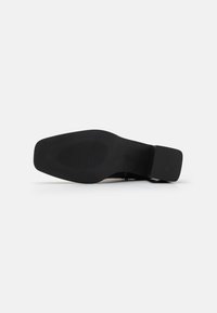 Semelle de chaussure noire au design lisse. Présente une forme rectangulaire et une surface texturée pour une adhérence optimale. Accent de talon élégant.