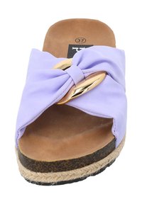 Lila slip-on sandal med en knuten rosett, gulddetalj och en naturligt tanad sula med vävd jute-textur. Storlek 37 visas.