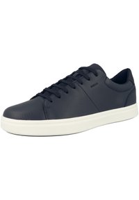 Zapatilla de cuero negro con acabado texturizado, suela de goma blanca y cordones tradicionales. Diseño minimalista con una sutil marca en el lateral.