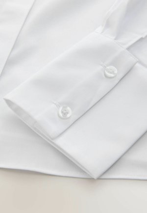 Bílá košile s manžetou s dvěma bílými knoflíky, hladká bavlněná tkanina a čistý, upravený design bez viditelných vzorů.
