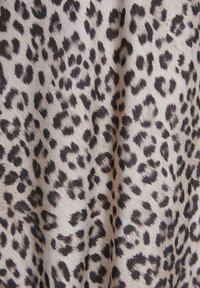 Tela de leopardo con un fondo beige, que presenta manchas negras y marrón oscuro de diferentes tamaños, textura suave y ligero brillo.