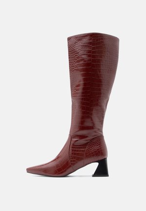 Knee-high red faux-crocodile leather boots with pointed toe and a textured finish, featuring a black angular heel.
