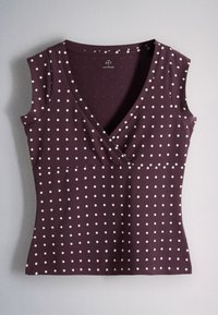 Sleeveless dark purple wrap top with a white polka dot pattern and a V-neckline, laid flat on a gray surface.