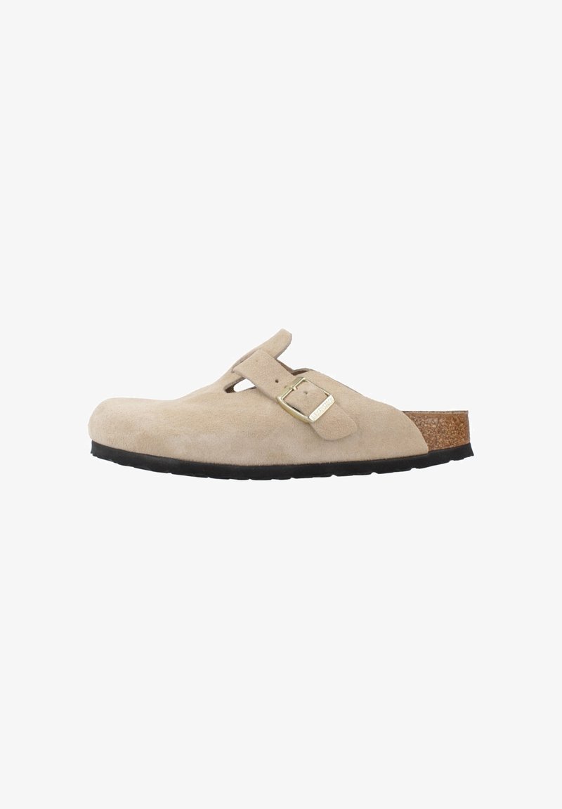 Beige suede instapschoen met een ronde neus, verstelbare band, kurken voetbed en een zwarte rubberen zool voor grip.