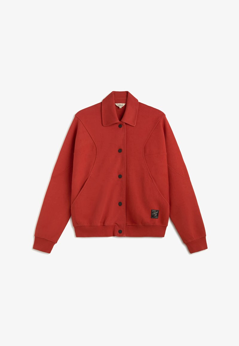 Veste rouge à manches longues avec boutons-pression noirs, col, poches latérales et petit écusson logo noir près de l'ourlet inférieur à l'avant.