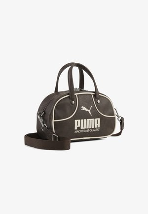 Torba Puma w ciemnym brązie z jasnobeżową lamówką, dwoma uchwytami, odpinanym paskiem na ramię oraz "PUMA MACHT'S MIT QUALITÄT" nadrukiem z przodu.