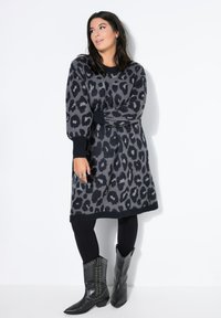 Grijs gebreid jurkje met zwart luipaardprint, geribde halslijn en boorden. Gepaard met zwarte cowboylaarzen met studs en zwarte leggings.